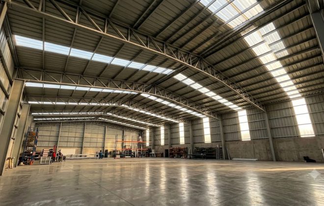 Interior de galpón industrial iluminado de forma natural mediante franjas de policarbonato PV4 en la cubierta y muros