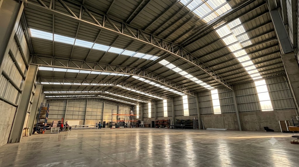 Interior de galpón industrial iluminado de forma natural mediante franjas de policarbonato PV4 en la cubierta y muros